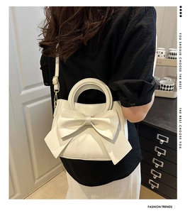 Detail showing back view of chic white crossbody bag with large bow and gold hardware