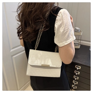 Détail d'un sac à rabat blanc tressé avec bandoulière en chaîne dorée sur mannequin