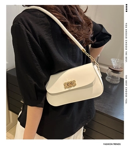 Detail of white leather shoulder bag with gold textured metal buckle and chain strap
