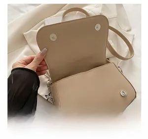 Détail des boucles magnétiques argentées sur un sac à bandoulière minimaliste de couleur crème