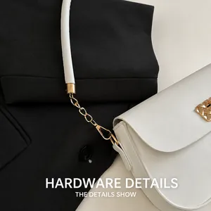 Close-up of golden hardware lock and chain details on a minimalist white leather shoulder bag