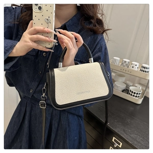 Détail d'un petit sac à bandoulière bicolore montrant sa texture tissée et sa sangle