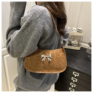 Détail du sac hobo léopard avec un nœud métallique argenté sur une finition marron