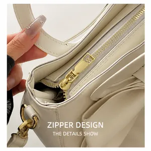 Detailed close-up of smooth white leather texture and gold metal zipper hardware on bag