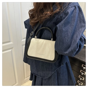 Vue détaillée du mini sac bandoulière en paille avec finitions en cuir noir sur mannequin