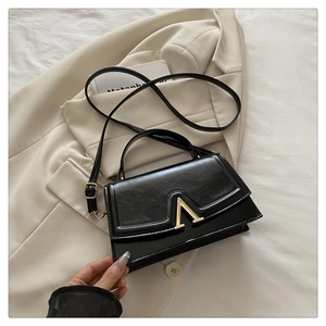Detail of glossy pleated black leather texture and gold V-shaped metal hardware buckle