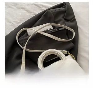 Close-up of cream bow handbag showing adjustable shoulder strap and gold hardware detail