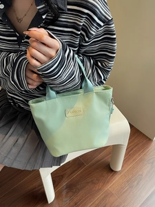 Minimalist mint green nylon tote bag with fashion label shown from a 45-degree angle