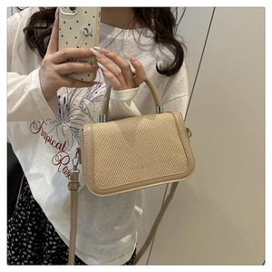 Détail du sac bandoulière tissé beige avec logo métallique et sangle en cuir