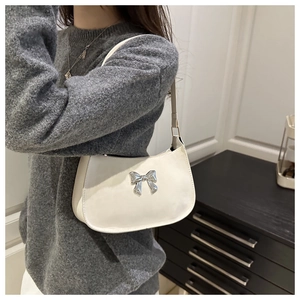 Gros plan du sac sous le bras blanc brillant avec nœud papillon argenté porté par mannequin