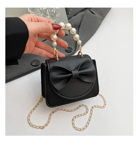 Detailed macro view of black pebbled leather texture with elegant pearl handle and gold chain