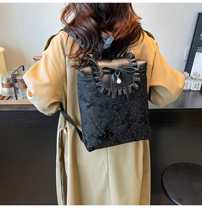 Detail of black backpack featuring delicate butterfly embroidery and pearl bow charms