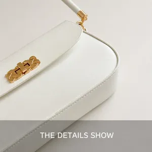 Detail shot of precise stitching and gold metal buckle on white leather crossbody bag