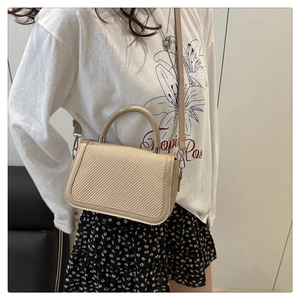Détail du petit sac tissé beige avec boucles argentées et bandoulière amovible