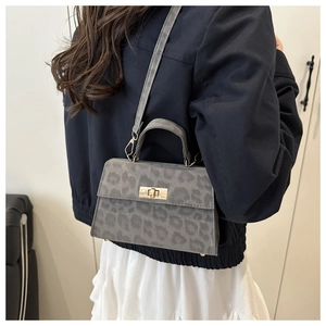 Detail der grauen Handtasche mit Leopardenmuster und goldenem Drehverschluss