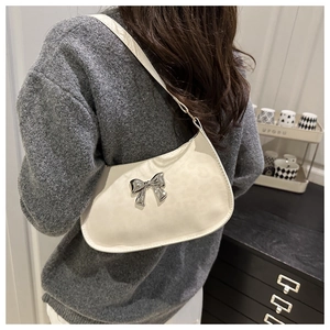 Détail du sac hobo blanc avec nœud papillon et texture léopard porté à l'épaule