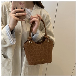 Detail of leopard print bucket bag with gold lettering and polished metal hardware