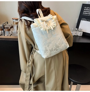 Detail of white butterfly-textured backpack with elegant ruffle trim and pearl bow charm