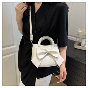 Macro detail of white bow handbag with matte PU leather and gold metal buckle