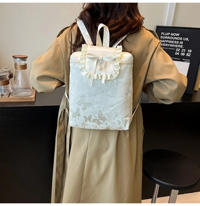 Detailed view of white girls backpack featuring lace ruffles and a silk bow with pearl