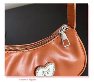 Detail eines silbernen Reißverschlusses auf strukturiertem braunem Leder mit Herzflicken