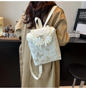 Close-up of a white backpack with butterfly prints, ruffle edges, and a pearl pendant
