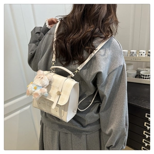 Detail of a chic cream mini backpack with plaid pattern and a plush bear pendant on model