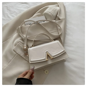 Close-up of cream white leather handbag featuring a signature gold V-shaped metal lock