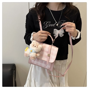 Detail of pink plaid crossbody bag featuring a cartoon bear print and plush charm