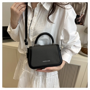 Détail d'un mini sac à main en cuir noir avec rabat tissé posé sur un bureau de bureau