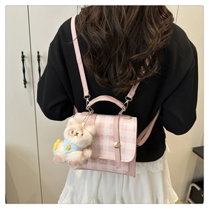 Detail of pink and white checkered bag with plush bear charm worn by a model
