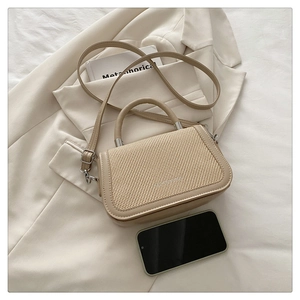 Détail d'un mini sac à main beige en paille et cuir avec smartphone pour échelle de taille