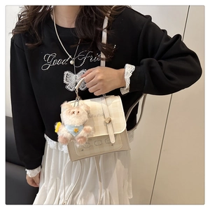 Quilted beige crossbody bag with teddy bear charm shown on model for size and style
