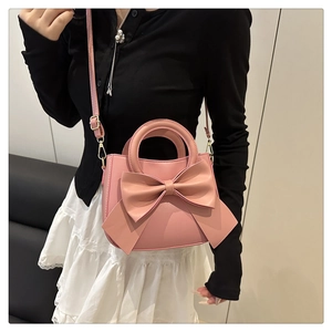 Detailed view of pink bow-knot handbag with gold hooks and smooth synthetic leather texture