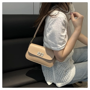 Détail du sac beige avec boucle rectangulaire sertie de cristaux et bandoulière en chaîne
