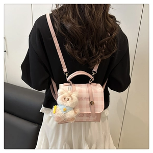 Pink checkered mini backpack on a model's back featuring a plush bear pendant accessory