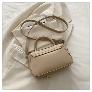 Détail du sac en cuir beige avec rabat en paille tressée et finitions métalliques