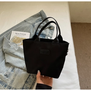 Dettaglio della borsa tote nera in nylon con etichetta Fashion e cerniera