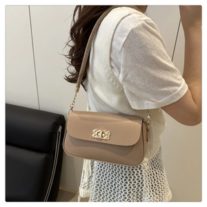 Detail showing the khaki matte leather crossbody bag with woven gold metal lock closure