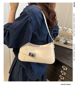 Détail du sac demi-lune blanc crème avec boucle argentée porté sur une robe en jean bleu