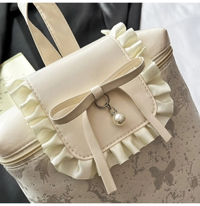 Detail of ruffled beige backpack flap featuring a bow, pearl pendant, and butterfly print