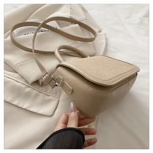 Détail du rabat en tissu tissé et cuir lisse sur un sac à main beige élégant