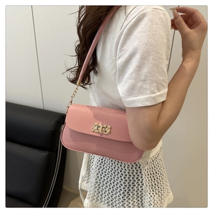 Detail of pink leather shoulder bag featuring a gold woven texture metal clasp on model