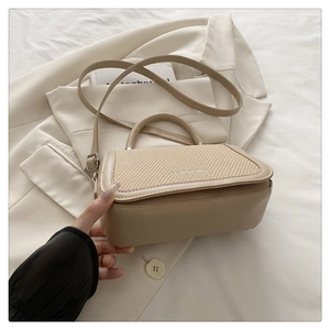 Détail du sac à bandoulière en cuir tressé beige avec garniture argentée sur tissu