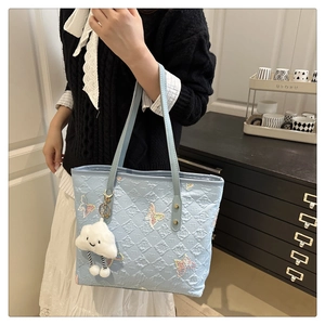 Détail du sac fourre-tout matelassé bleu clair avec broderie papillon et breloque