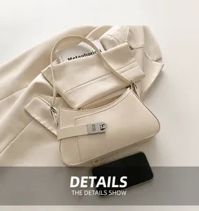 Détail du sac sous le bras en cuir beige avec boucle argentée sur costume beige