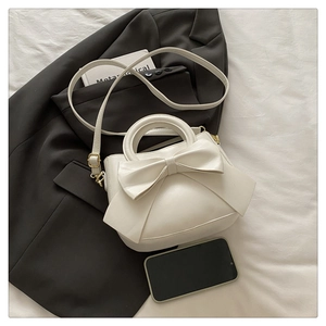 Detailed texture of off-white bow handbag with adjustable golden buckle strap