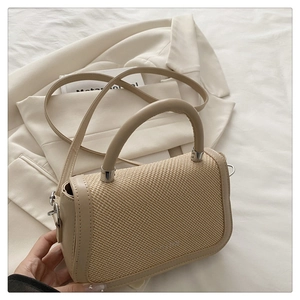 Détail de la texture du tissu tissé et de la poignée en cuir beige du sac à bandoulière