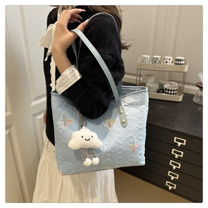 Detail of light blue quilted tote bag featuring butterfly sequins and cloud charm accessory