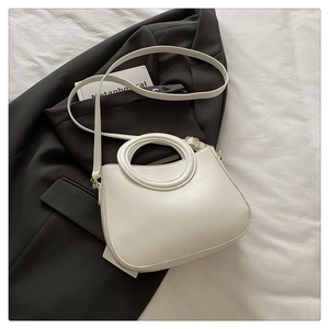 Detail of off-white minimalist handbag featuring circular handle and leather strap